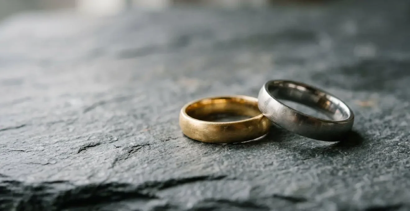 Paire d'alliances de mariage en or et platine posées sur une surface minérale naturelle avec lumière douce
