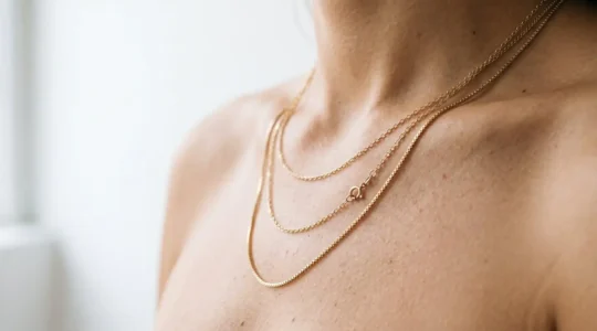 Chaînes fines en or superposées sur décolleté créant un effet minimaliste et lumineux
