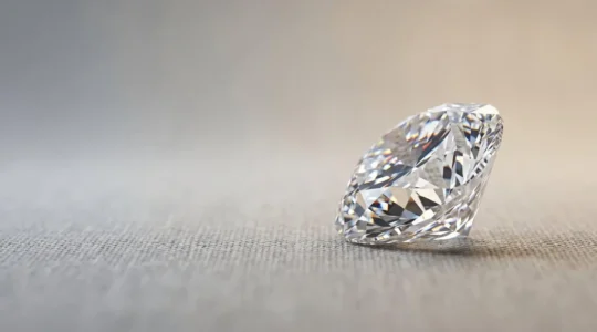 Diamant naturel posé sur surface neutre avec éclats de lumière révélant sa brillance