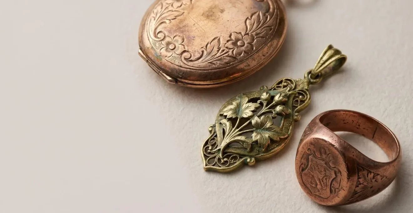 Gros plan sur des bijoux anciens en or aux teintes variées, rouge russe, vert Belle Époque et rose victorien, disposés sur une surface naturelle